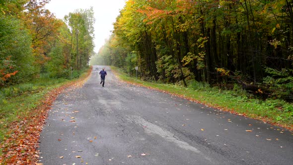 Man running on a small road surrounded by maple autumn maple leaf slowmotion