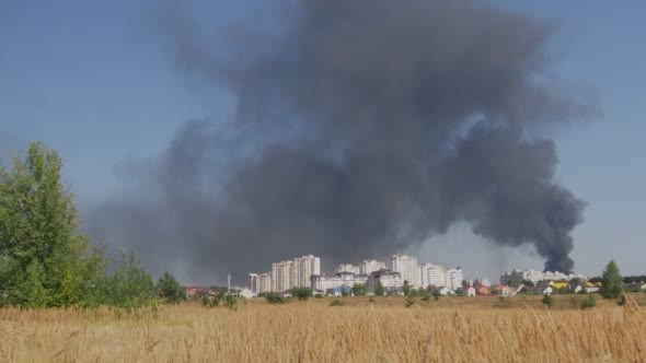 Black Smoke Rises above the City in the Distance