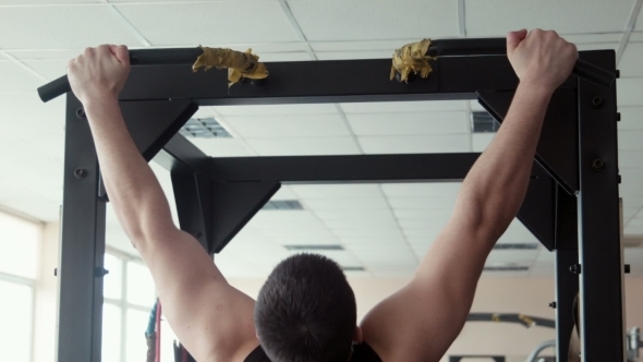 Male Bodybuilder Pulling Up in a Gym