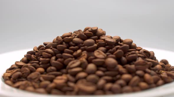 Pile of coffee on a white plate rotates on a light background.