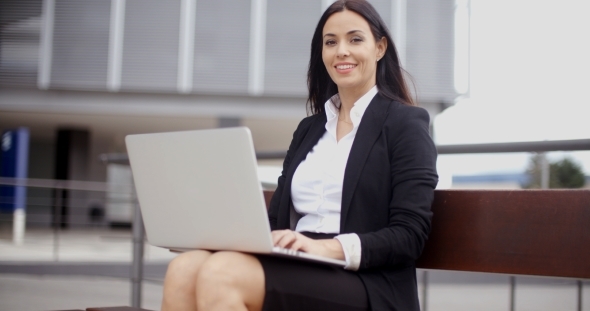 Smiling Female Worker With Laptop On Bench alt