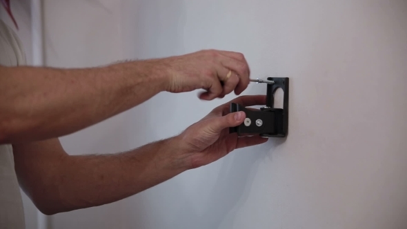 Man Installs The Holder Bracket  On The Wall