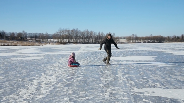Father And Daughter Sledding On Frozen Lake
