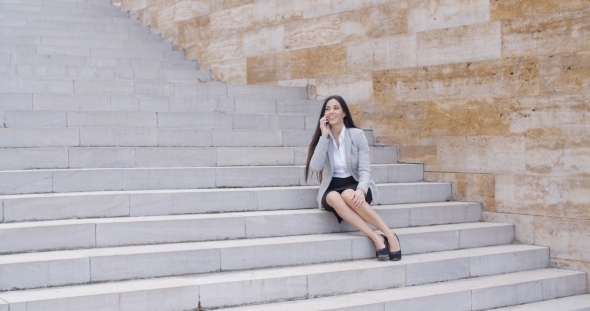 Happy Executive With Phone And Seated On Stairs alt