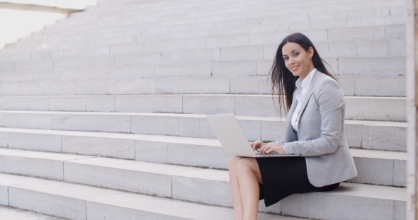 Smiling Woman Using Laptop On Stairs alt