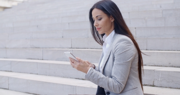 Pretty Young Worker Sitting On Steps With Phone alt