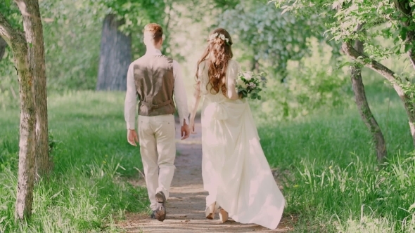Young Beautiful Couple Walking In The Park Holding Hands