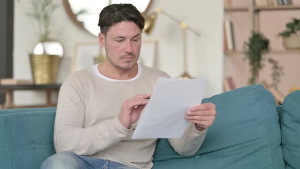 Middle Aged Man Reading Documents , at Home