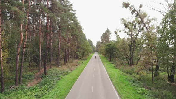 Cyclist is riding on road bike on empty road in forrest. Professional triathlete is cycling on bike