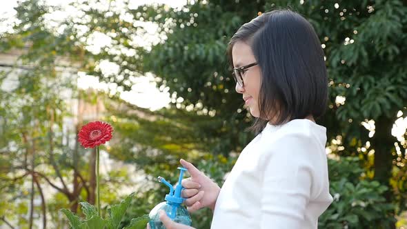 Asian Girl Watering Flower On Summer Day