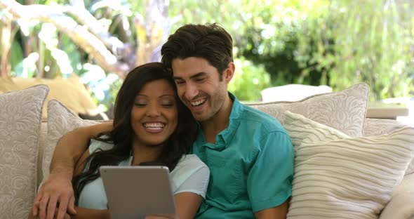 Young couple sitting on sofa and using digital tablet in living room