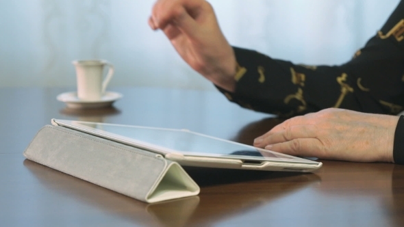 Woman Works Using a Digital Tablet. Drinks Coffee