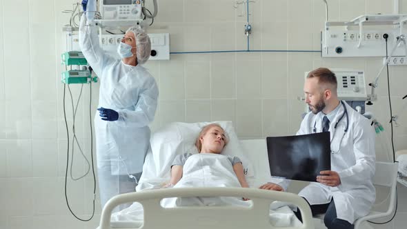 Male Doctor Talking to Female Patient in Hospital Bed