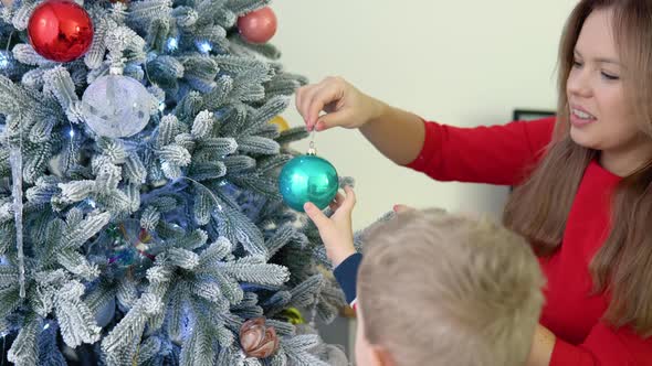 Little Boy Helping His Mom to Decorate Christmas Tree