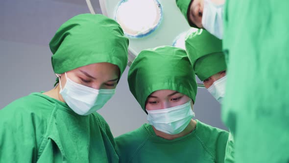 Group of doctors working in hospital operating room come to open the light and start the operation.