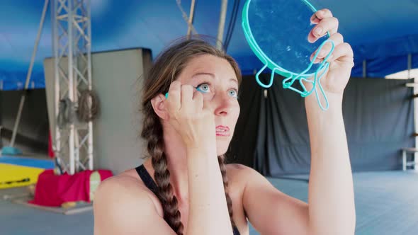 Circus artist applying make up, holding mirror