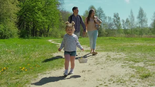 Happy Family Resting in Nature Near the Forest