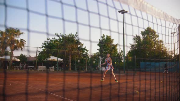 A Young Woman Playing Tennis on the Court  View Through the Net