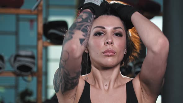 Tattooed Woman Moves Away Hair From Her Face and Stands in Fighting Pose