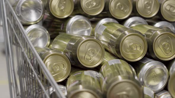 Lots of Gold Beer Cans in a Grocery Cart in a Supermarket