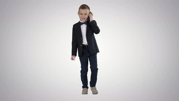 Little Boy in a Costume Making a Phone Call While Walking on Gradient Background.