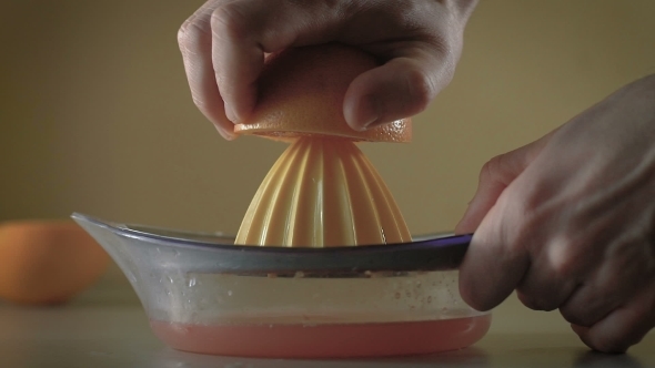 Hand Squeezes Fresh Grapefruit Juice In The Kitchen