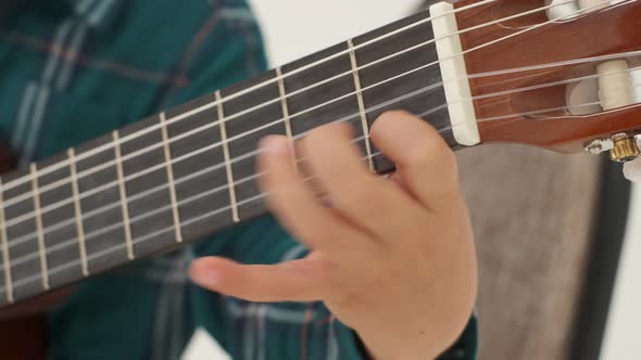 Little Boy is Playing Big Classical Guitar Sitting on the Stool