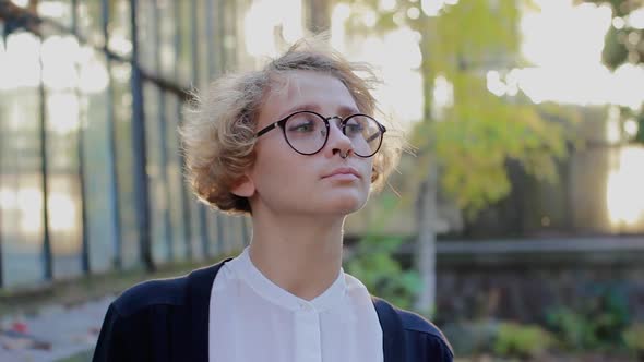 Portrait of Dreaming Blonde Woman Wearing Glasses, Looking at Right and Taking Off Glasses
