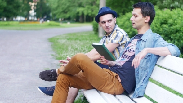 Friends Talking About Book On Bench In Park Look At Watch And Leave