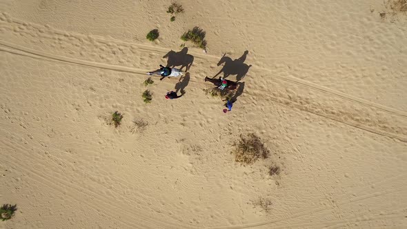 Aerial view of people riding horses in the desert of Al Khatim in Abu Dhabi.