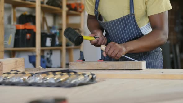 Carpenter carving wood with hammer at table 4k