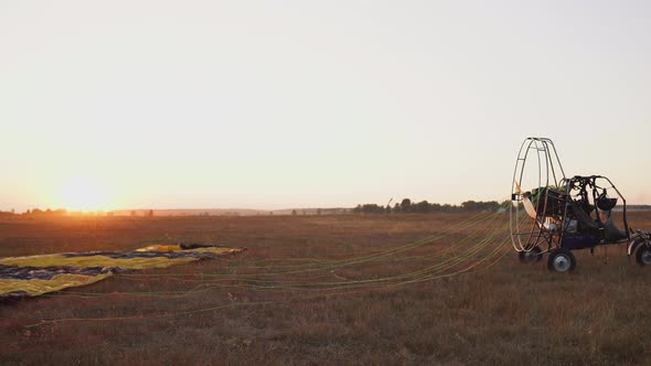 Motor Paraglider Ready To Fly in the Sky Against the Setting Sun in Warm Sunlight.