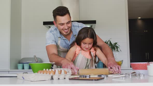 Happy caucasian father and daughter baking together in kitchen