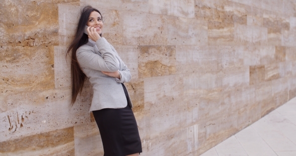Happy Woman Talking On Phone And Leaning On Wall alt
