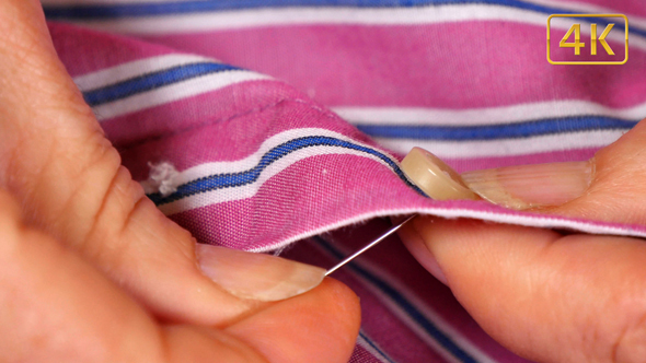 Seamstress Sewing a Button on a Shirt 4K