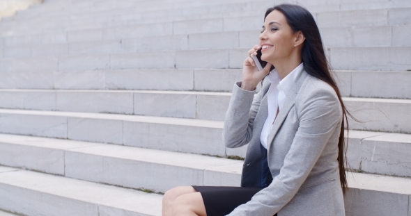Laughing Woman Sitting On Steps With Phone alt