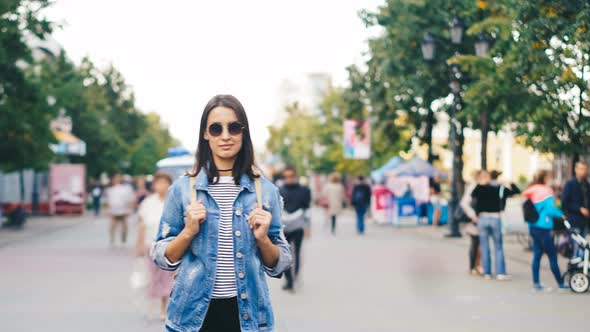 Time-lapse Portrait of Confident Young Lady in Sunglasses Standing in City Center Among Running