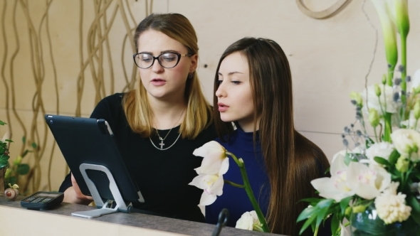 Two Young Woman Working With The Tablet In a Flower Shop