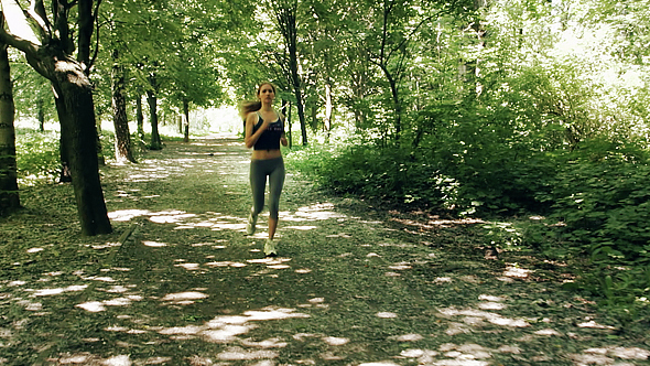 Young Cute Girl Runs In The Park Under The Trees alt