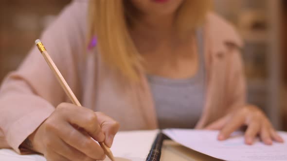 Young undergraduate girl do homework, read textbook, study hard for knowledge on lecture desk.