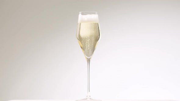 Air Bubbles Rise in a Modern Glass of Champagne on White Background