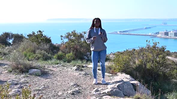 African Woman with Dreadlocks is Dancing Against Mountain and Sky