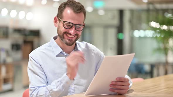 Excited Businessman Reading Documents and Celebrating in Office 