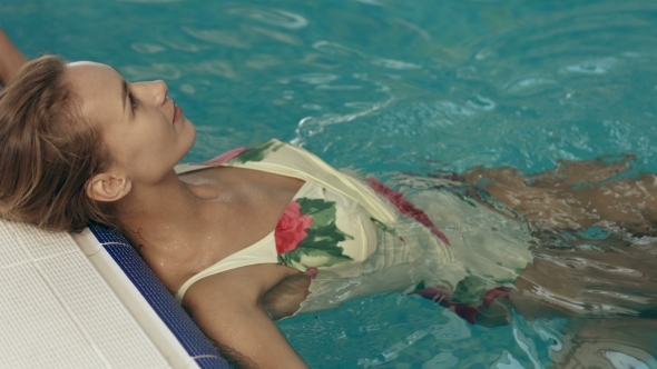 Girl in a Swimsuit Recline Against The Edge of The Pool alt
