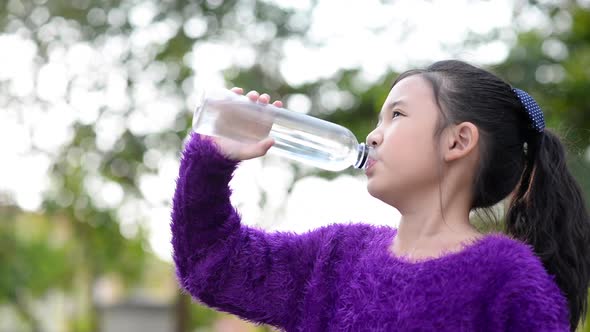 Beautiful Asian Girl Drinks Water From A Bottle Outdoors