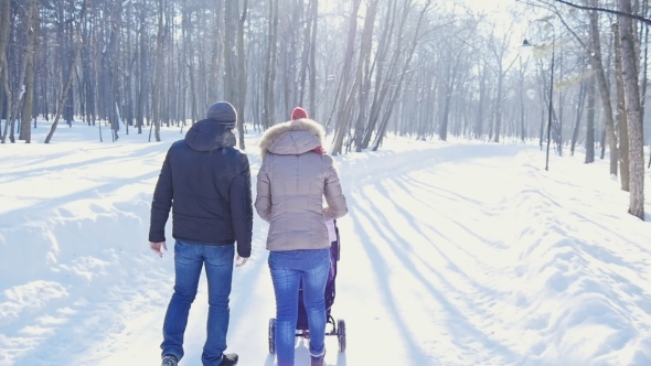 Happy Young Family Walking In The Park In Winter