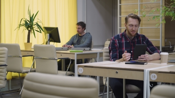 Man Talking On Headphones Using The Tablet Through The Internet. alt
