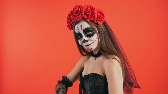 Day of Dead Lady with Skull Makeup Inviting you to Go with Her By Hand Gesture and Smiling Posing on