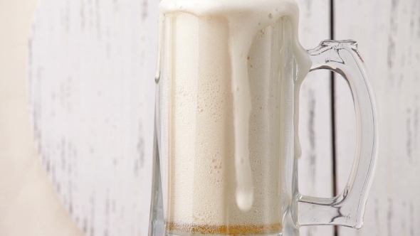 Pour The Beer Into a Glass On a Wood Background