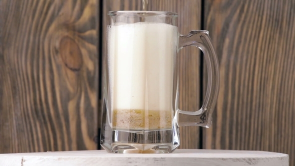 Pour The Beer Into a Glass On a Wood Background